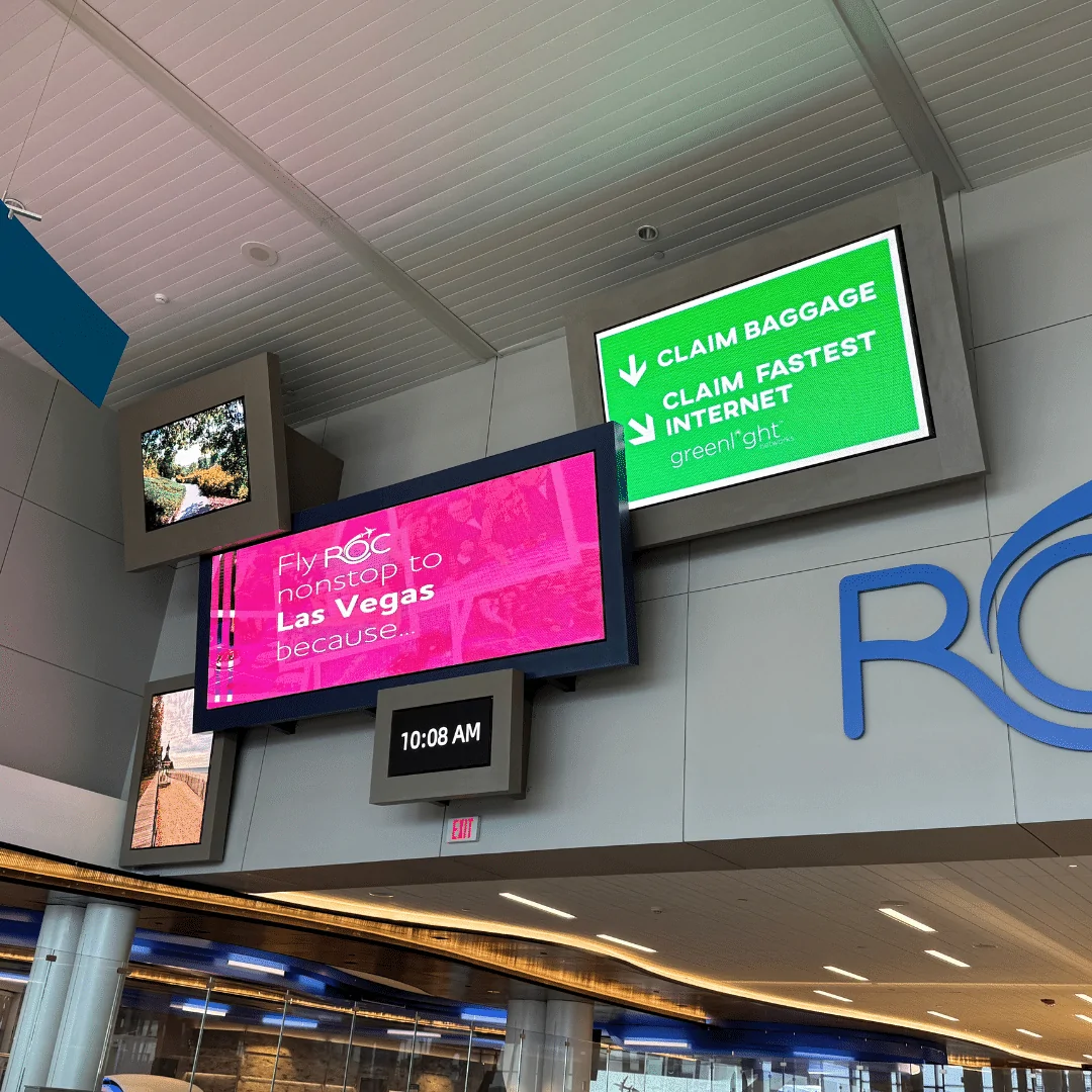 Empty classroom with rows of desks facing a large LED display showing a vivid sunset interface and educational icons.