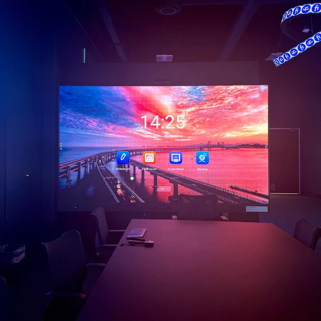 Empty classroom with rows of desks facing a large LED display showing a vivid sunset interface and educational icons.
